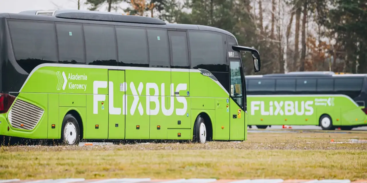 Dwa zielone autokary Flixbus stojące na trawiastym terenie.