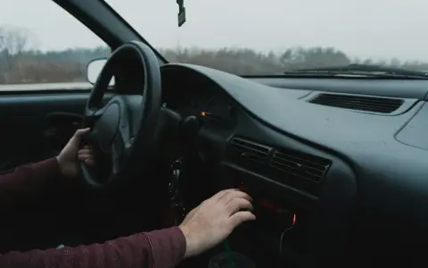 Dłoń kierowcy reguluje radio samochodowe.