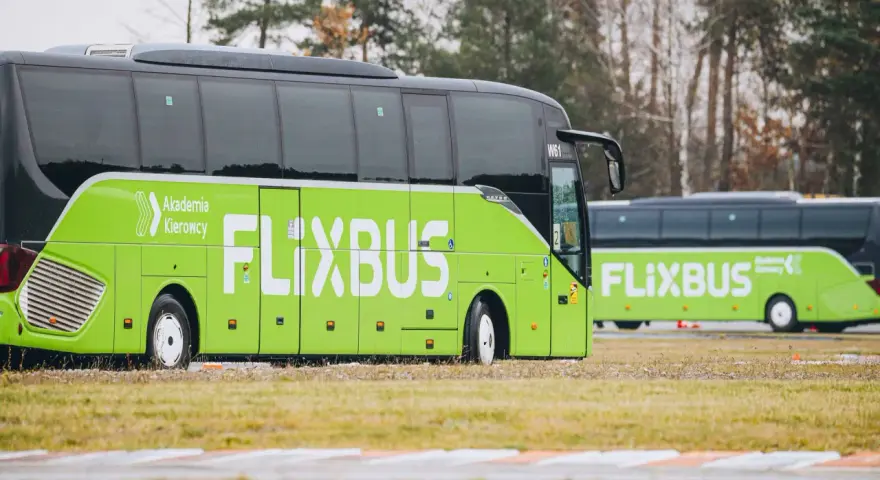 Dwa zielone autokary Flixbus stojące na trawiastym terenie.