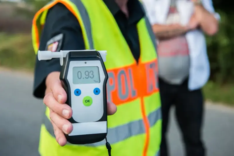 Policjant w kamizelce odblaskowej trzyma alkomat z wynikiem 0.93 promila.